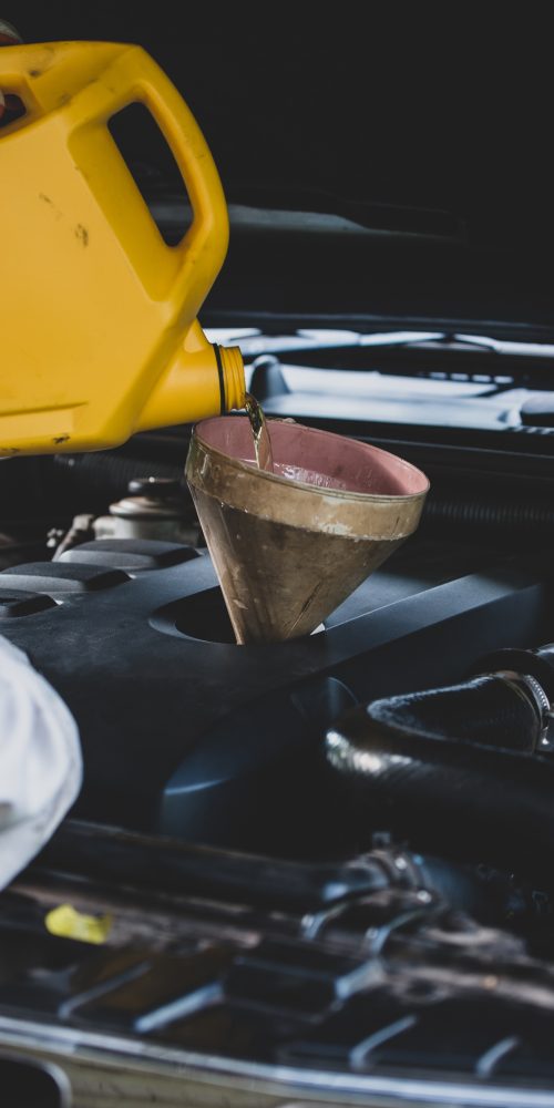Auto mechanic pouring lubricant oil Malaysia during routine engine maintenance
