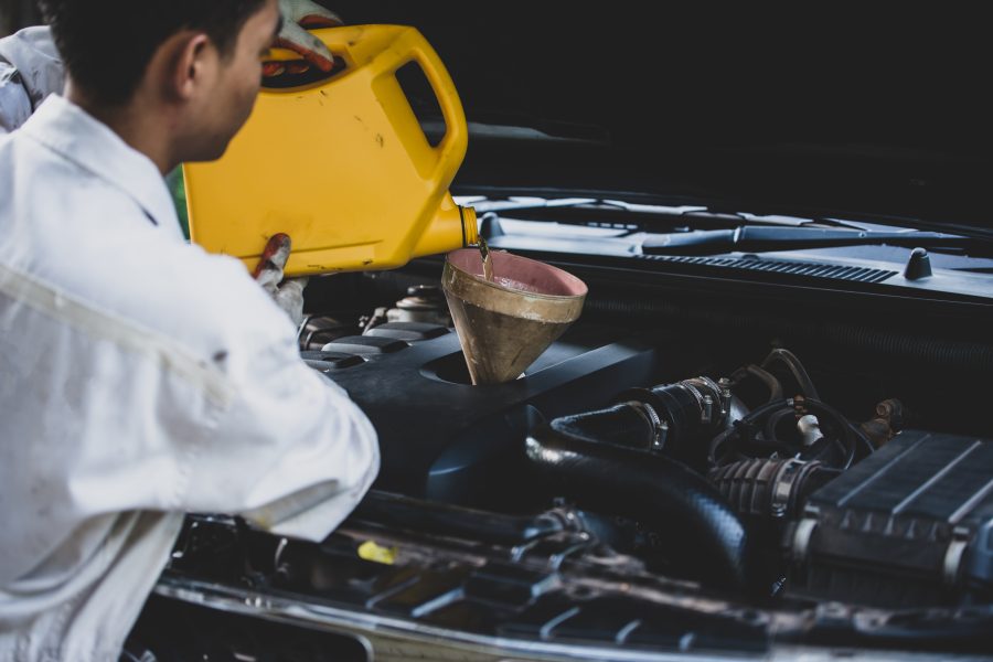 Auto mechanic pouring lubricant oil Malaysia during routine engine maintenance