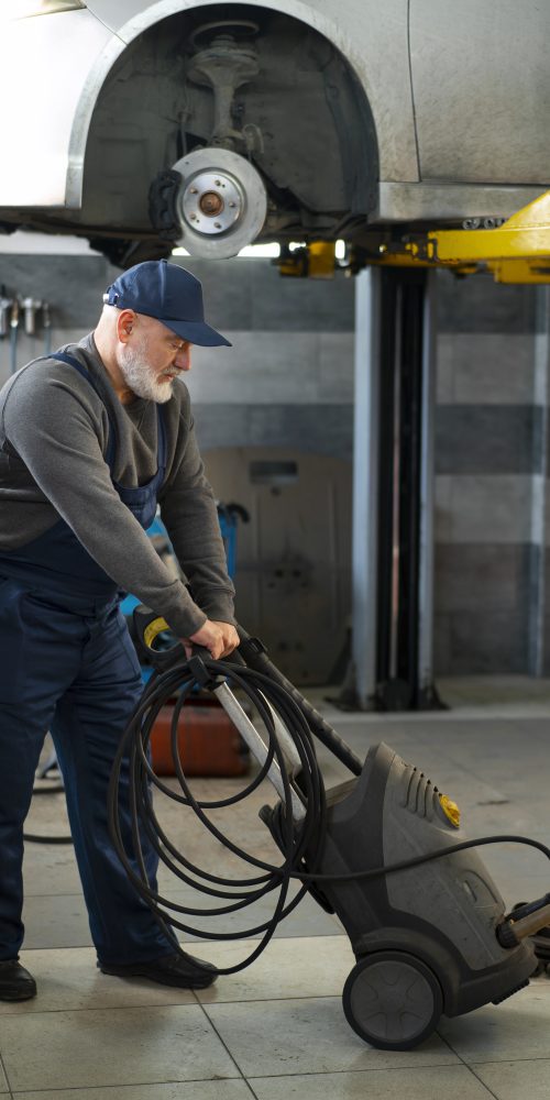 Male car mechanic using a cleaning machine in an automotive repair shop